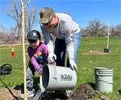 A young child learns how to plant a tree.