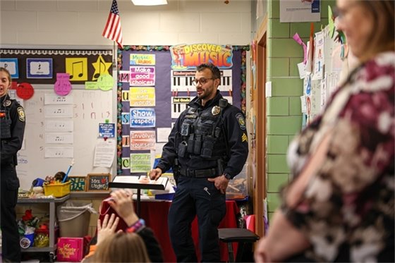 male officer talking to kids at a school