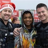 Two Roseville Police Officers pose for a picture with a young man during the annual Shop with a Cop shopping spree.
