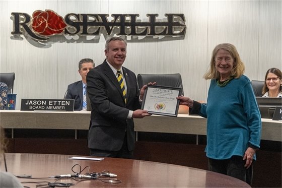 Mayor Dan Roe hands a Roseville resident a Sustainable Steward Award.