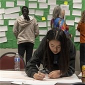 A woman writes ideas on a piece of paper to be added to the idea wall at an Envision Roseville community visioning event.