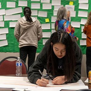 A woman writes an idea on a piece of paper for the idea wall at an Envision Roseville event.