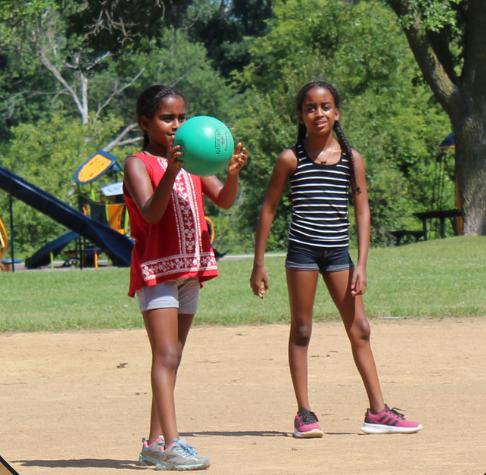 Two children in a baseball field playing kickball