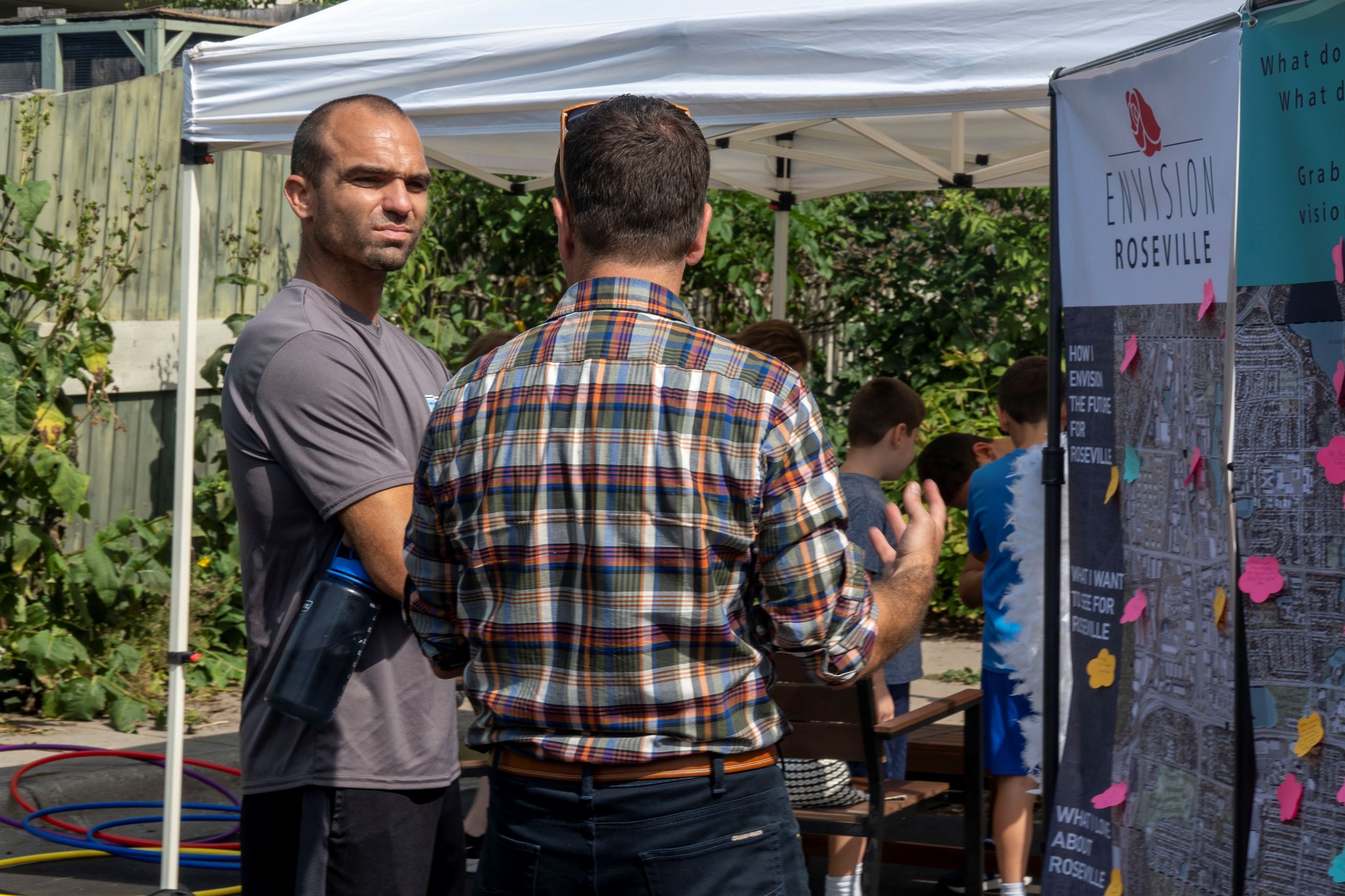 Two people talk at the Envision Roseville booth at Wild Rice Festival.