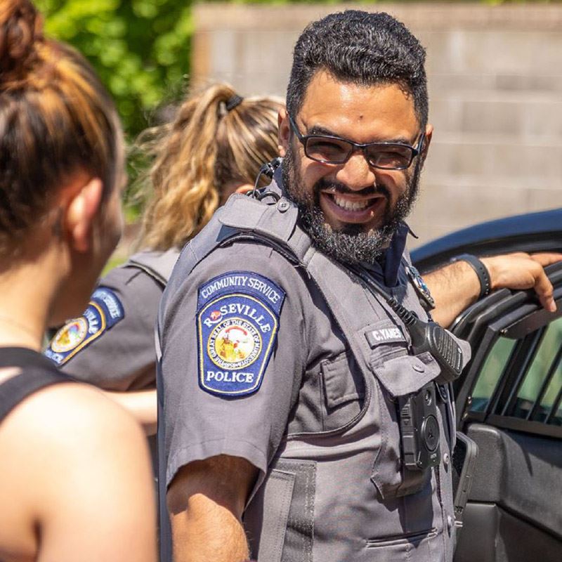 A Roseville Community Service Officer smiles while talking to a community member.